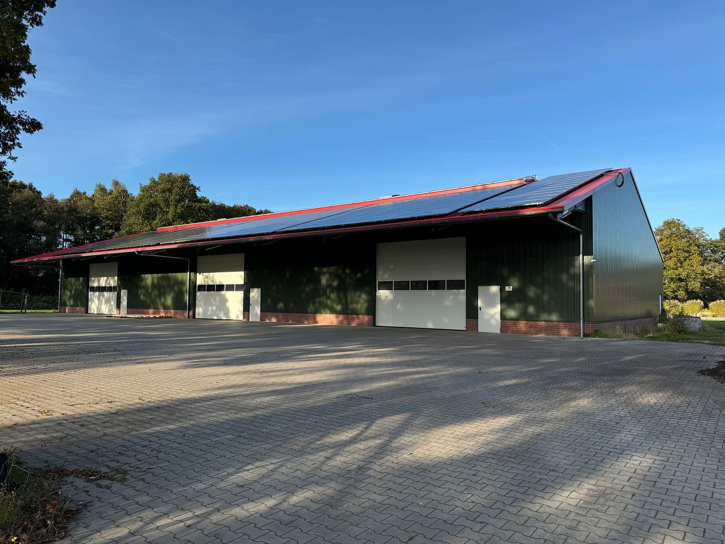 Großes Gebäude mit Solarpanelen auf dem Dach, das nachhaltige Energieerzeugung symbolisiert.